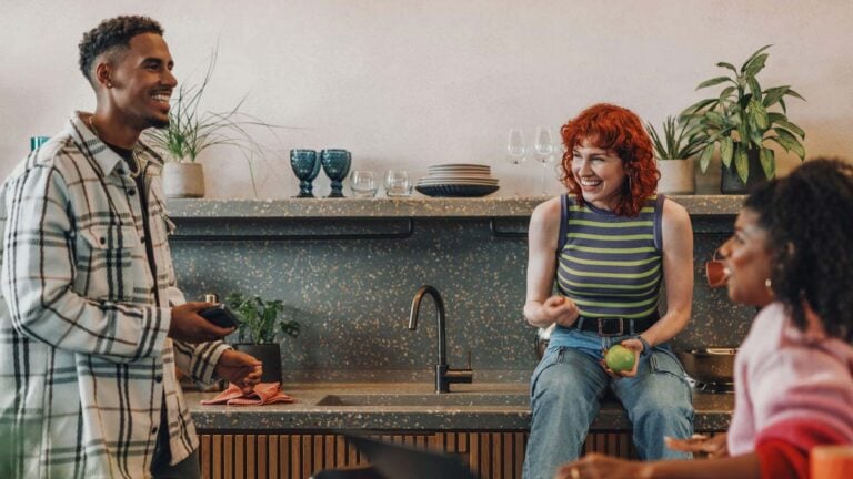 young adults hanging out in a kitchen.