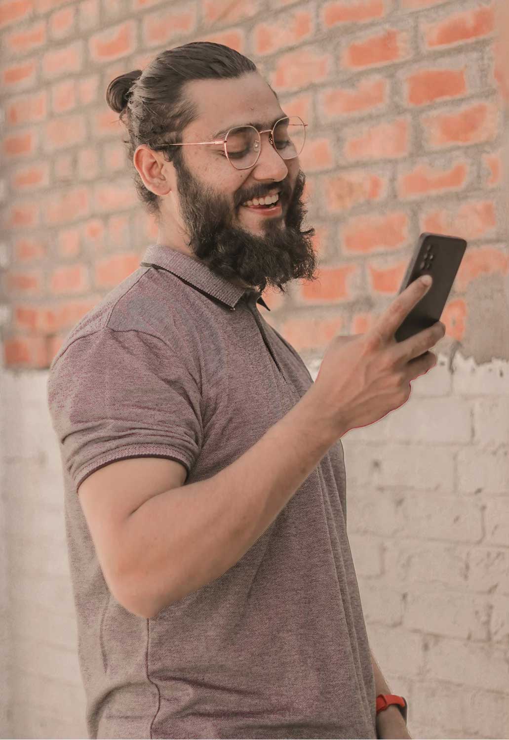 man smiling while looking at his iphone.