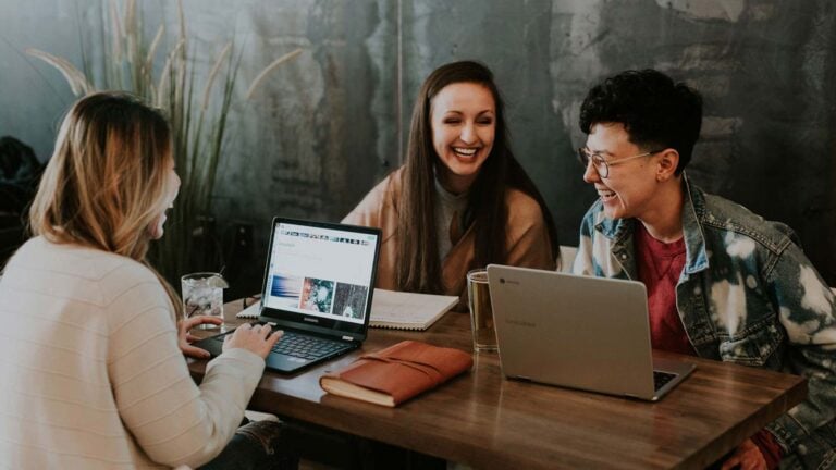 young adults on computers sharing a laugh.