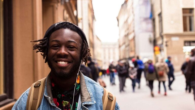young man with headphones walking down a street.