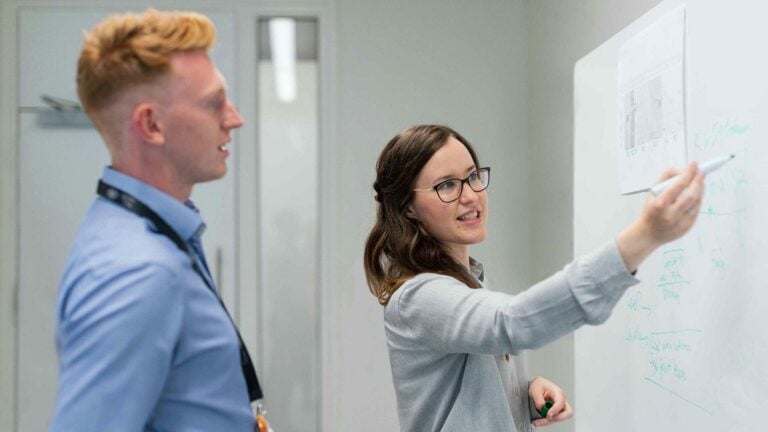 marketing man and woman using a whiteboard to outline strategy.