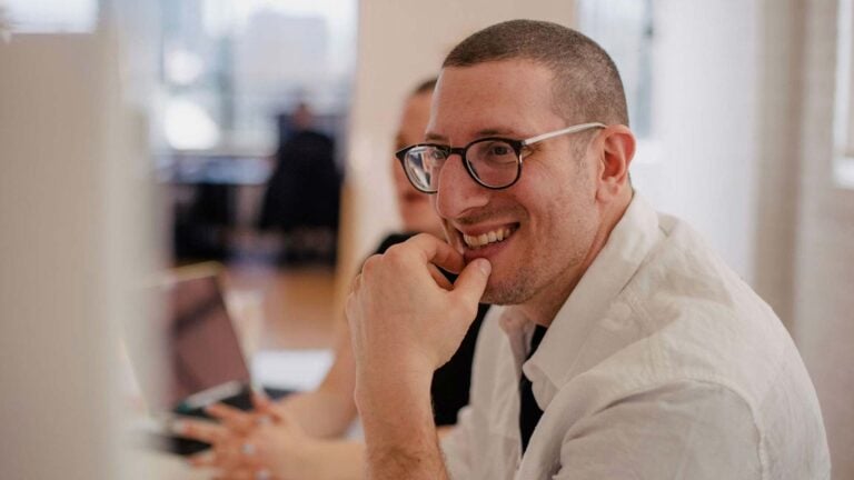 man smiling looking at a computer screen.