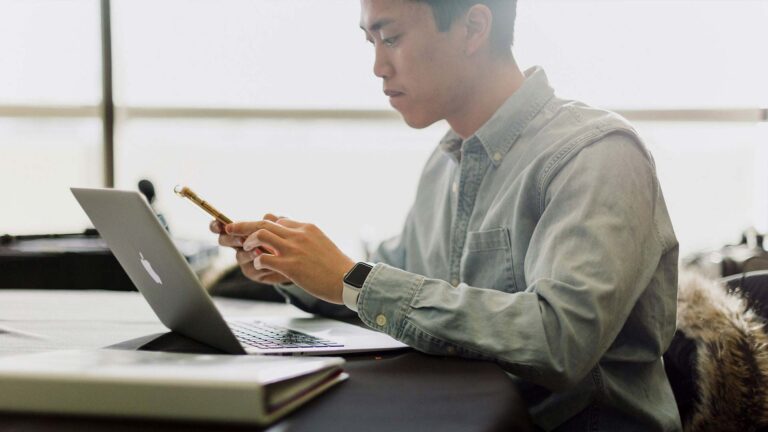 young man on iphone with laptop.